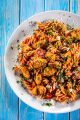 Pasta with tomato sauce and vegetables on wooden table