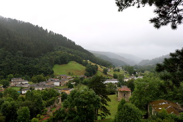 Fototapeta premium Village and mountains with gray sky, fog and rain