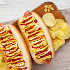 Homemade colombian hot dogs with pineapple sauce, yellow mustard and mayo ketchup on a rustic wooden board, view from above. Flat lay, top view, overhead. Closeup.