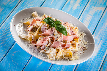 Pasta carbonara on white plate on wooden table
