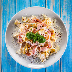 Pasta carbonara on white plate on wooden table