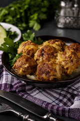 Meatballs in curry sauce in bowl against a dark background, vertical orientation