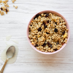 Overhead view, pink bowl of fruit granola and honey. Flat lay, top view, from above.
