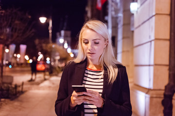 Worried young woman texting on smart phone outdoor in the evening