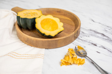 Fresh Acorn Squash Cut in Half with Seeds Scooped out of One Half; Seeds and Spoon on Countertop