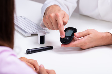 Doctor Showing Lancet And Glucose Meter To Female Patient