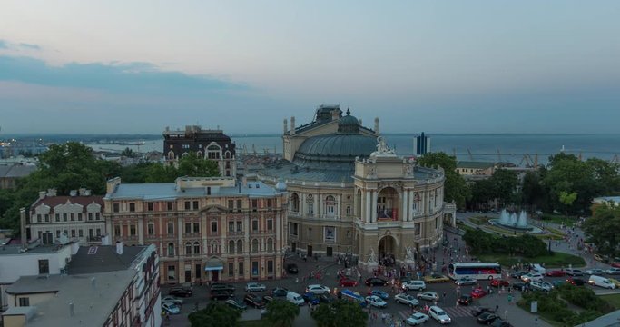 Time lapse of Odessa Opera House during sunset against the backdrop of the Black Sea and Odessa port. People leave the theater. The movement of cars on a narrow street near the theater. Ukraine