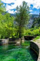 Fototapeta premium South of France, view on small Provencal town of poet Petrarch Fontaine-de-vaucluse with emerald green waters of Sorgue river