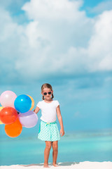 Adorable little girl playing with balloons at the beach