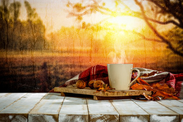 White wooden table background with mug and board with autumn background.