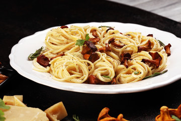 pasta with organic chanterelles. portion of spaghetti pasta with fried chanterelles in a creamy garlic sauce with cheese on a table