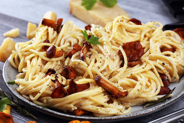 pasta with organic chanterelles. portion of spaghetti pasta with fried chanterelles in a creamy garlic sauce with cheese on a table