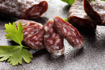 salami cut. thinly sliced salami on a wooden texture on the background.