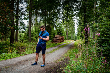Mann mit Smartphone und Rucksack im Wald