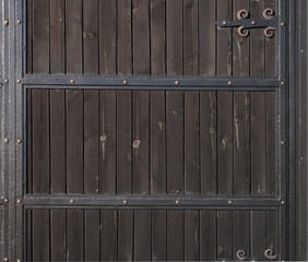 Brown wooden gate with forged metal stripes. Backgrounds and textures. Close up