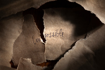 Torn Paper of the Word Impossible creating the Word Possible