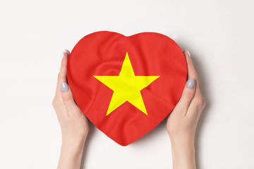Flag of Vietnam on a heart shaped box in a female hands. White background