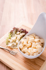 Palmitos picados sobre recipiente blanco en tablas de madera