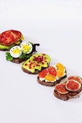 Six different toasts on the white background. Assorted toasts with eggs, fruits and berries, avocado and tomatoes.