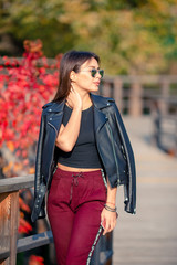 Fall concept - beautiful woman drinking coffee in autumn park under fall foliage