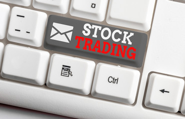 Conceptual hand writing showing Stock Trading. Concept meaning Buy and Sell of Securities Electronically on the Exchange Floor White pc keyboard with note paper above the white background