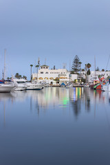 Blue hour at marina Port El Kantaoui, beautiful boats, yachts and ships parked in the reflective sea, restaurants and gift shops