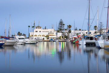 Blue hour at marina Port El Kantaoui, beautiful boats, yachts and ships parked in the reflective sea, restaurants and gift shops