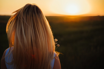  Blond girl turned to sunset. Close-up