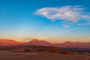 Fototapeta na wymiar A majestic sunbeam at sunset in the Moon Valley of the Atacama desert with the Licancabur volcano peak, Chile.