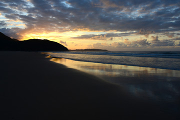Fototapeta premium empty beach in Portugals Algarve with reflecting clouds in wet sand during sunset
