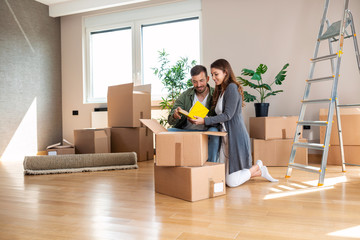 Happy couple unpacking boxes in their new apartment