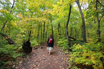 young woman walking in the forest with red backpack