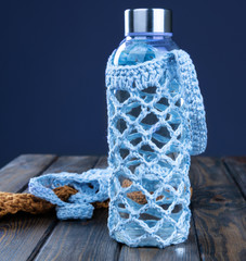 Close-up of a water bottle in a blue case on a wooden table