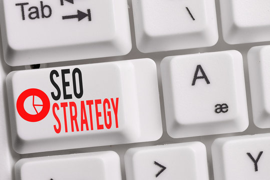 Conceptual hand writing showing Seo Strategy. Concept meaning Techniques and tactics to increase the visitors of a website Keyboard with note paper on white background key copy space
