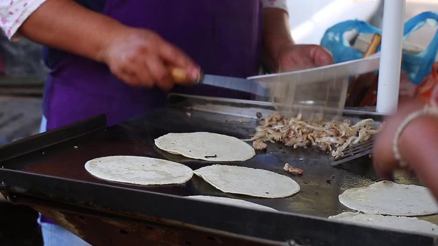 Mujer cocinando tacos en puesto ambulante