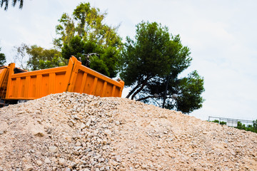Sand as a building material in a quarry, next to an orange truck.