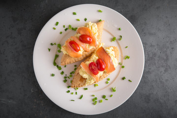 Healthy breakfast. Puff with butter, scrambled eggs, fresh salted salmon, tomatoes and greens