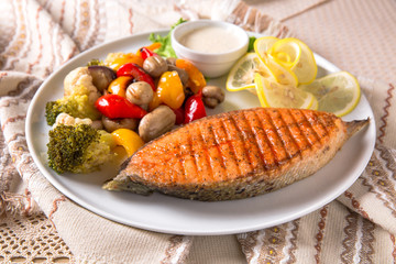 Grilled salmon steak. Juicy delicacy red fish on a plate with a salad of fried vegetables. Balkan cuisine. Restaurant menu