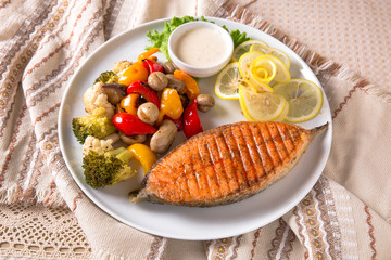 Grilled salmon steak. Juicy delicacy red fish on a plate with a salad of fried vegetables. Balkan cuisine. Restaurant menu