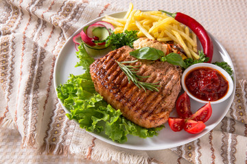 Grilled pork steak. A juicy piece of meat with vegetables, mushrooms, sauce and French fries. Restaurant menu. Isolated on white