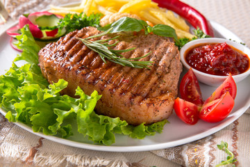 Grilled pork steak. A juicy piece of meat with vegetables, mushrooms, sauce and French fries. Restaurant menu. Isolated on white