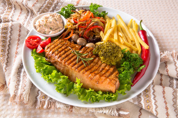 Grilled pork steak. A juicy piece of meat with vegetables, mushrooms, sauce and French fries. Restaurant menu. Isolated on white