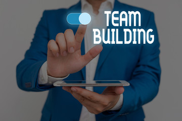 Word writing text Team Building. Business photo showcasing Types of activities used to enhance social relations Male human wear formal work suit presenting presentation using smart device