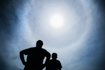 Silhouette of people watching a solar eclipse with halo around sun