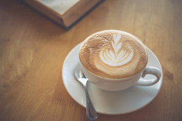 Latte coffee in glass placed on wooden floor.