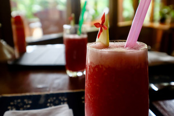 close up a glass of red watermelon juice on restaurant table. Blur glass and window background