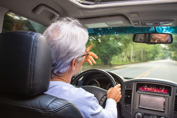Senior man driving vehicle on narrow road with nature