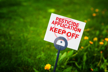 Pesticide applicaton sign with treated grass and dandelion weeds