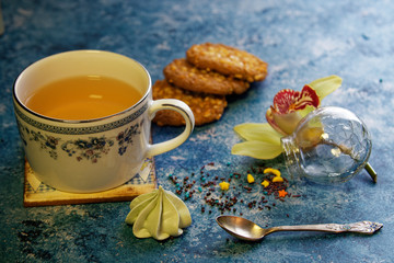 Obraz na płótnie Canvas tea in a porcelain cup with cookies on a blue background