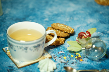 tea in a porcelain cup with cookies on a blue background